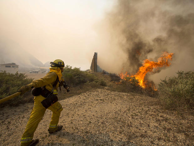 A firefighter rushes to extinguish the wildfire at the naval base at Point Mugu, Calif., May 3, 2013. 