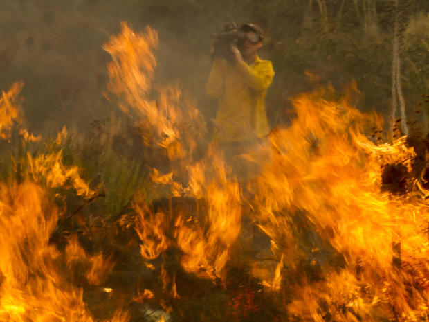 A cameraman records the wildfire burning along the Pacific Coast Highway near Ventura, Calif., at Point Mugu May 3, 2013. 