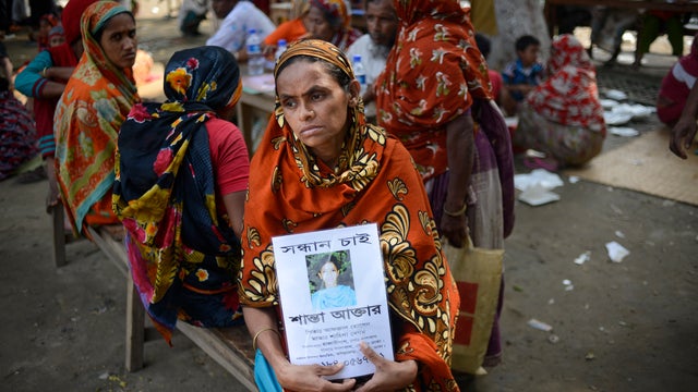 A Bangladeshi woman holds a portrait of her missing daughter at a makeshift morgue for victims of a factory collapse in Savar 