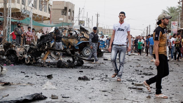 Iraqi security forces and civilians inspect the scene of a car bomb attack in the Kamaliyah neighborhoo 