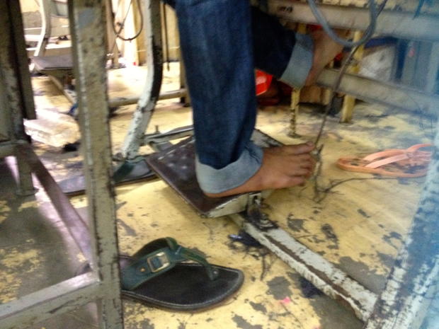 A man's foot works the pedal of a sewing machine in a garment factory in Dhaka 