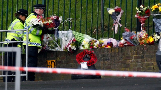 Police officers lay down floral tributes handed to them by members of the public May 23, 2013, at the scene of a deadly attack in Woolwich, southeast London. 