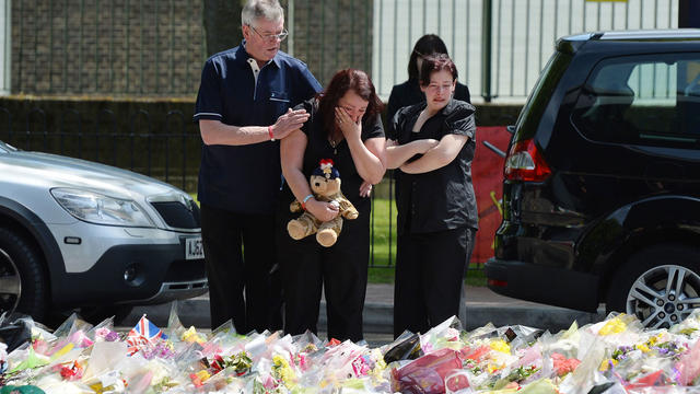 Lyn Rigby, mother of Drummer Lee Rigby, holding a teddy bear joins other family members as they look at floral tributes outside Woolwich Barracks left by well wishers as they visited the scene of the 25-year-old soldier's murder in Woolwich, south-east Lo 