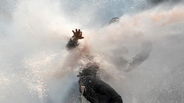 A protester tries to remain standing as police water cannon fires water during clashes at the Taksim Square in Istanbul Tuesday, June 11, 2013.  