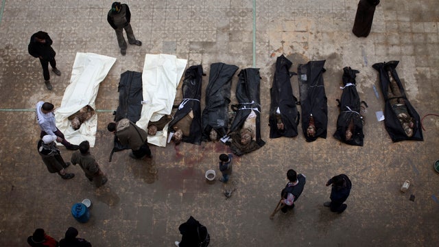 Syrian men search for their relatives among the bodies of civilians executed and dumped in the Quweiq river, in the Bustan al-Qasr district of Aleppo 