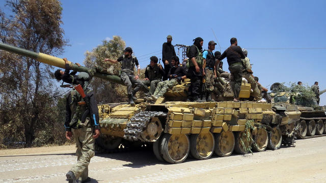 Rebel fighters stand on top of two tanks reportedly confiscated from an army barracks in the northwestern Syrian city of Sermin on June 14, 2013.  