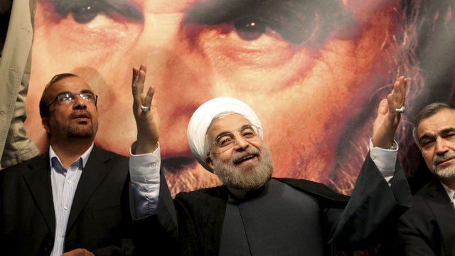 In front of a portrait of the late Iranian revolutionary founder Ayatollah Khomeini, presidential candidate Hasan Rowhani, a former top nuclear negotiator, center, gestures to his supporters at a rally in Tehran, Iran, Saturday, June 1, 2013.  