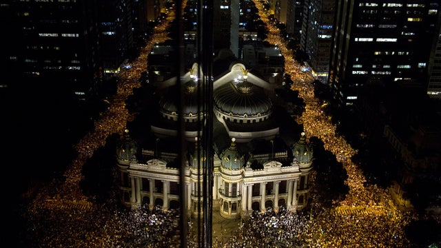 Protestors are reflected on the glass of a building, left, as they march in Rio de Janeiro, Brazil, Monday, June 17, 2013. Protests in Sao Paulo, Rio de Janeiro and other Brazilian cities, set off by a 10-cent hike in public transport fares, have clearly  