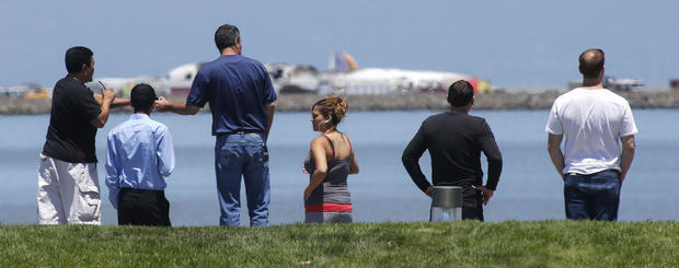 People look at the wreckage of Asiana Flight 214 where it crashed at San Francisco International Airport on July 6, 2013. 