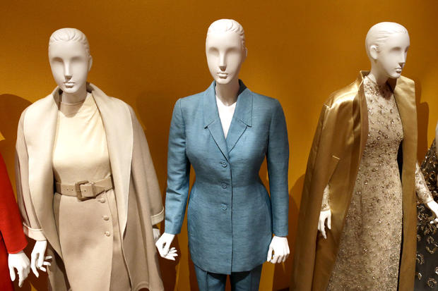 An Oscar de la Renta pantsuit, center, worn by Former first lady Hillary Rodham Clinton, is displayed next to other creations by the designer at the Clinton Presidential Library in Little Rock, Ark., Monday, July 8, 2013. The "Oscar de la Renta: American Icon" exhibit is on display at the Clinton library until Dec. 1. 
