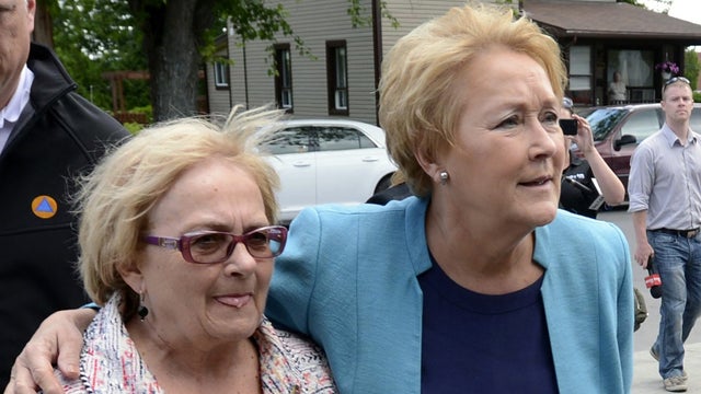 Quebec Premier Pauline Marois, right, puts her arm around Lac-Megantic, Quebec Mayor Colette Roy-Laroche as she arrives Thursday July 11, 2013, to tour the site of Canada's worst railway catastrophe in almost 150 years, after a runaway oil train killed 50 