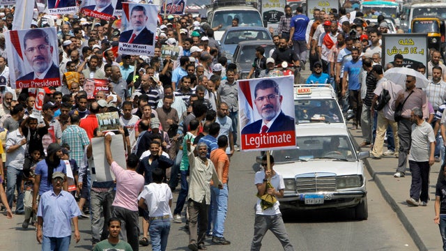 Supporters of Egypt's ousted President Mohammed Morsi hold his posters as march in Cairo 