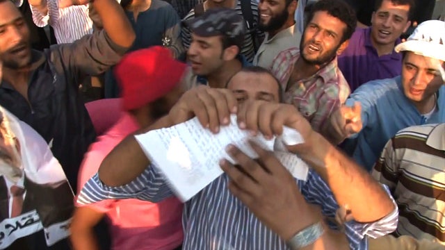 A supporter of ousted Egyptian President Mohammed Morsi rips a flyer from the country's interior ministry, dropped via helicopter, waring the protesters to leave. 