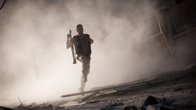 A Syrian rebel fighter runs after attacking a tank with a rocket-propelled grenade during fighting in the Izaa district in Aleppo 