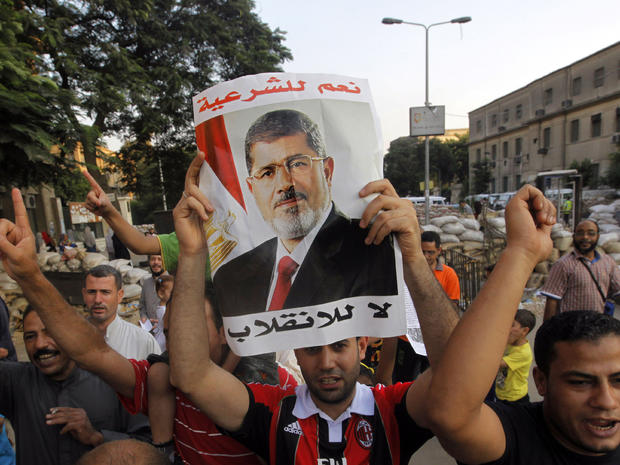 Supporters of Egypt's ousted President Mohammed Morsi walk through makeshift barriers to a sit-in at Nahda Square, which is fortified with multiple walls of bricks, tires, metal barricades and sandbags, where protesters have installed their camp near Cairo University in Giza, southwest of Cairo, Egypt, Saturday, Aug. 10, 2013. 