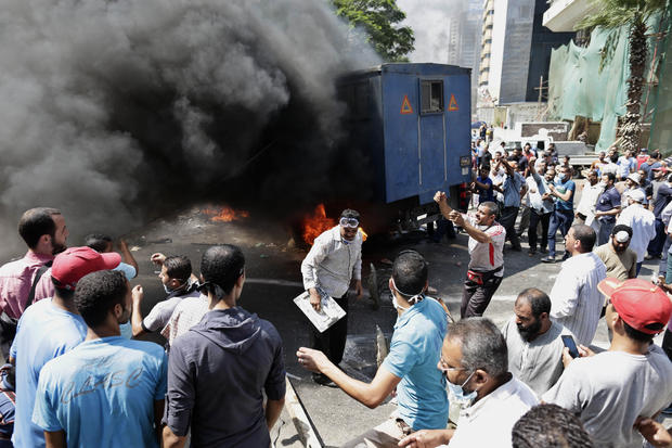 Supporters of ousted Islamist President Mohammed Morsi surround a burning police car during clashes with Egyptian security forces 