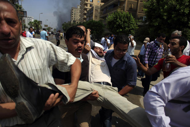 Supporters of Egypt's ousted President Mohammed Morsi carry a wounded man during clashes with Egyptian security forces 