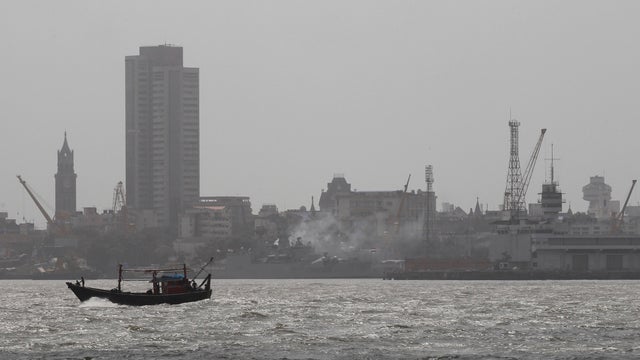 A boat passes a naval dockyard where an Indian navy submarine caught fire and sank after an explosion in Mumbai 