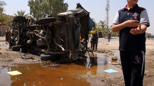 An Iraqi boy stands near a burnt-out car at the scene of a car bomb attack in Baghdad 