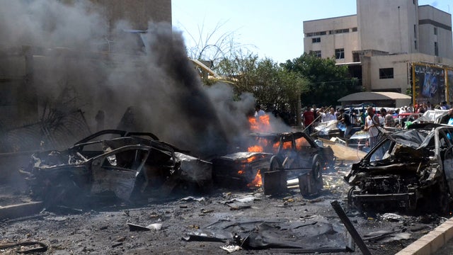 Burned and destroyed cars are seen at the entrance of a mosque, left, which was attacked by a car bomb in the northern city of Tripoli, Lebanon, Aug. 23, 2013. 