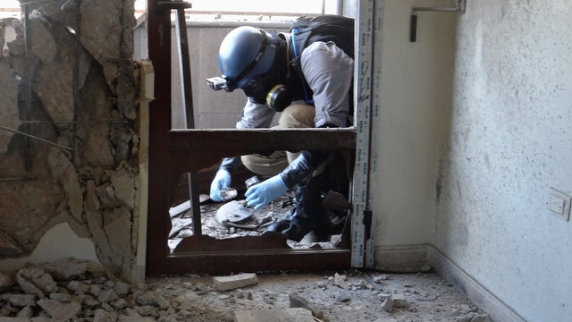 A United Nations arms expert collects samples at the site of an alleged chemical weapons attack in Damascus' eastern Ghouta suburbs 