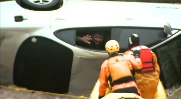 Emergency workers rescue trapped man from a car submerged in flood waters 