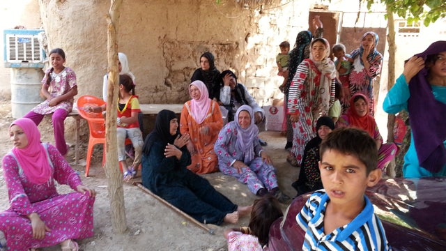 Iraqi women and children gather outside a Sunni mosque after a suicide bomber struck during Friday prayers in the village of Umm al-Adham 