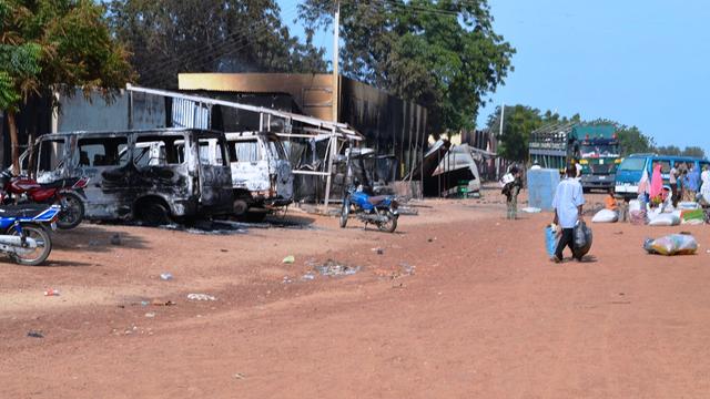 People walk past burnt vehicles and shops burnt by Boko Haram Islamists 