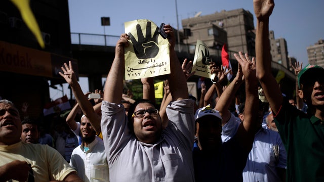 Supporters of Egypt's ousted President Mohammed Morsi chant slogans against Egyptian Defense Minister Gen. Abdel-Fattah el-Sissi during a protest in Cairo Oct. 4, 2013, and hold placards showing an open palm with four raised fingers, which has become a sy 