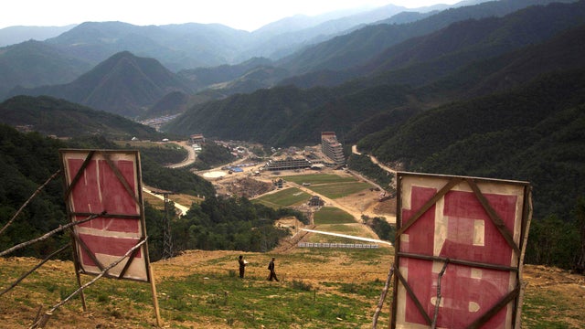 Propaganda signs stand at the top of a ski slope overlooking a building project to construct a ski resort at North Korea's Masik Pass 