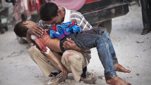 A Syrian man cries while holding the body of his son, killed by the Syrian Army, near Dar El Shifa hospital in Aleppo 