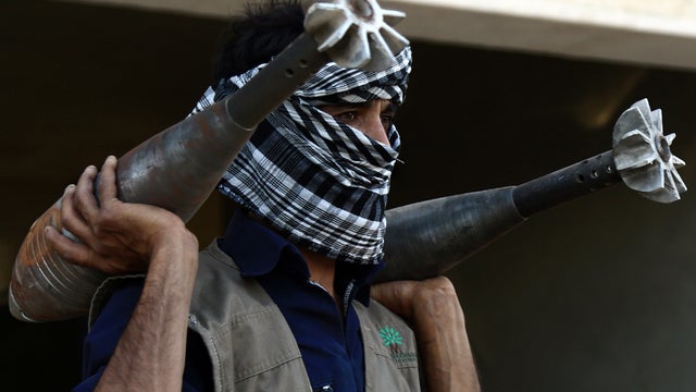 A rebel fighter carries homemade mortar rounds Sept. 3, 2013, in the northern Syrian city of Raqqa. 