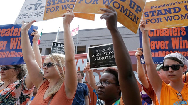 In this July 9, 2013, photo, opponents and supporters of an abortion bill hold signs outside the Texas Capitol. 