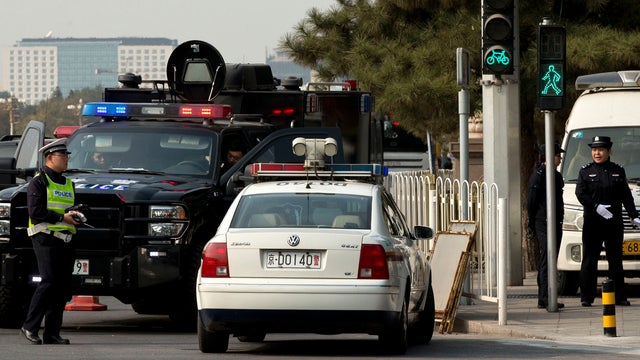Two policewomen, right, a traffic police, in yellow vest, and members of a SWAT team guard a street corner, where, on Monday, a sport utility vehicle veered into a crowd near Tiananmen Gate, where the car crashed and caught fire, in Beijing, China, Wednes 