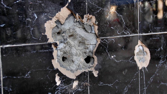 Shadows of local residents are reflected on a bullet-riddled wall of an Afghan bakery where Nasiruddin Haqqani, a senior leader of the feared militant Haqqani network, was assassinated in the Bhara Kahu area on the outskirts of Islamabad, Pakistan, Monday 