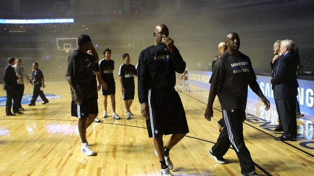 Players of the Minnesota Timberwolves leave as smoke engulfs the basketball court during a regular season NBA match between the Timberwolves and the San Antonio Spurs in Mexico City 