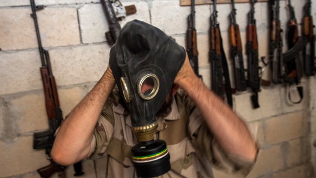A Syrian rebel tries on a gas mask seized from a Syrian army factory in the northwestern province of Idlib 