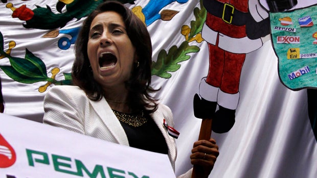 An opposition lawmaker shouts while holding a protest banner as dozens of leftist lawmakers take over the lower house trying to block discussion of the energy reform bill in Mexico City Dec. 11, 2013. 