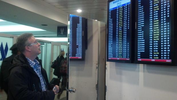 Man looks at cancellation board at LaGuardia Airport 