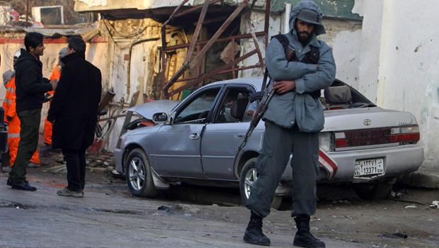An Afghan policeman stands near a damaged car outside a Lebanese restaurant, the site of a suicide attack, in Kabul Jan. 18, 2014. 