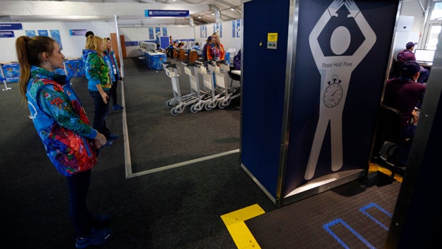 Volunteers wait to enter through a security checkpoint at the Coastal Village, where athletes will reside during the 2014 Winter Olympics, Jan. 29, 2014, in Sochi, Russia. 