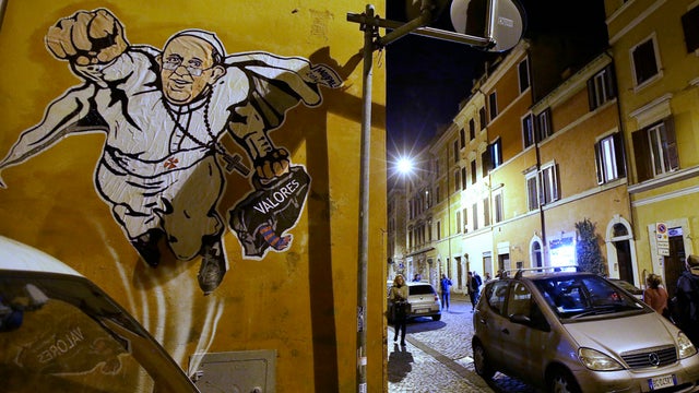 Graffiti depicting Pope Francis as a Superman-like hero, clutching a bag with the Spanish word for "Values," is seen on a wall of the Borgo Pio district near St. Peter's Square 
