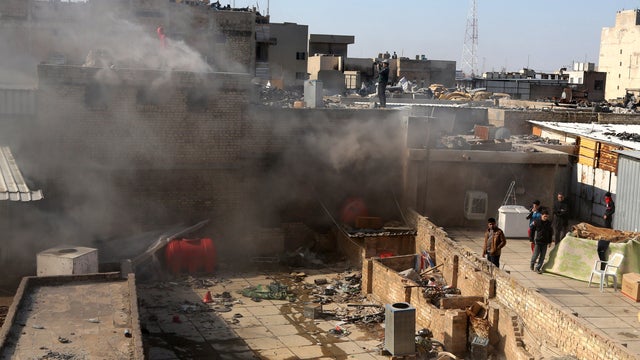 Civilians inspect the site after a parked car bomb went off at a commercial center in Khilani Square in central Baghdad, Iraq 