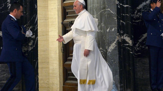 Pope Francis extends his hand to greet a guard as he walks out of St. Peter's Basilica at the Vatican 