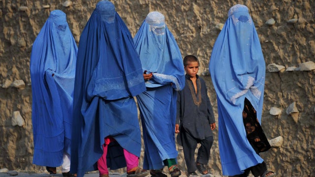 Burqa-clad Afghan women make their way on the outskirts of Jalalabad 
