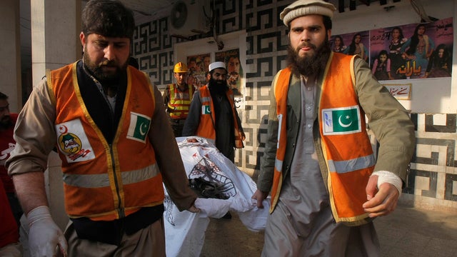 Pakistani rescue workers remove a body from the site of a grenade attack on a crowded movie theater in Peshawar 