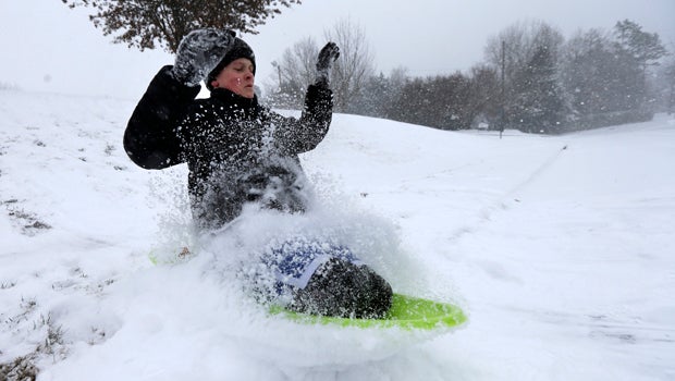 Stephen Clark, 12, hits a ramp made of snow as he sleds near his home in Charlotte, N.C., Feb. 12, 2014, as a winter storm moves into the area.