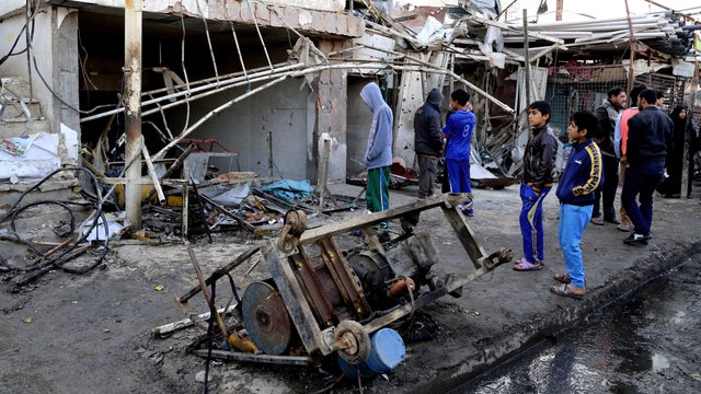 Civilians inspect the site of a car bomb attack in the eastern Ur neighborhood of Baghdad 