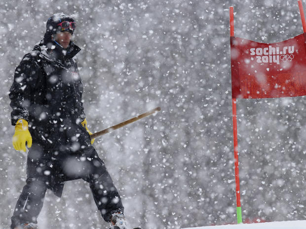 A ski course worker waits with a shovel under heavy snow fall just before the start of the second run of the women's giant slalom at the Sochi 2014 Winter Olympics, in Krasnaya Polyana 