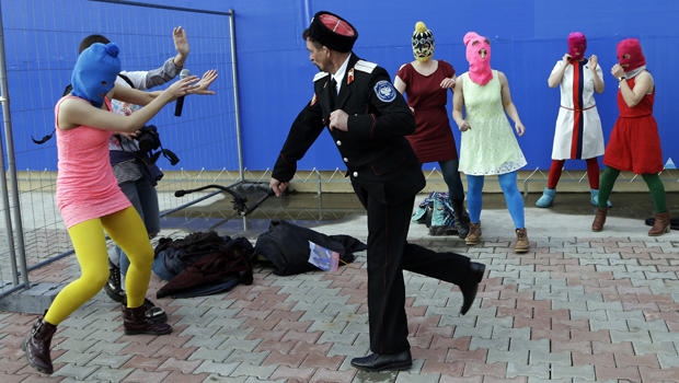 A Cossack militiaman attacks Nadezhda Tolokonnikova and a photographer as she and fellow members of the punk group Pussy Riot, including Maria Alekhina, center, in the pink balaclava, stage a protest performance in Sochi, Russia, Feb. 19, 2014. 